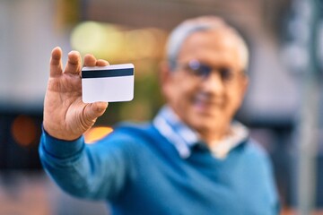 Wall Mural - senior grey-haired man smiling happy holding credit card at the city.