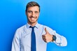 Handsome caucasian man wearing business shirt and tie smiling happy and positive, thumb up doing excellent and approval sign