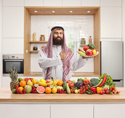 Sticker - Saudi arab man holding a plate of fresh fruits and vegetables in a kitchen