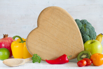 Wall Mural - Kitchen board in the shape of heart, vegetables, fruits and spoon. Healthy food concept