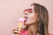 Beautiful woman in sunglasses licking pink ice cream in waffle cone