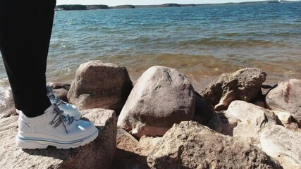 Wall Mural - Side view of a girl walking on stones on the beach of the Minsk Sea