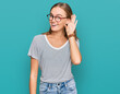 © Krakenimages.com - Beautiful young blonde woman wearing casual clothes and glasses smiling with hand over ear listening an hearing to rumor or gossip. deafness concept.