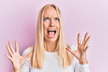 Canvas Print - Young blonde girl wearing casual clothes crazy and mad shouting and yelling with aggressive expression and arms raised. frustration concept.