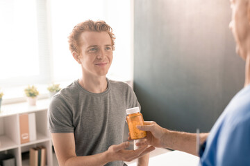 Aufkleber - Contemporary physiotherapist passing bottle of pills to young smiling patient