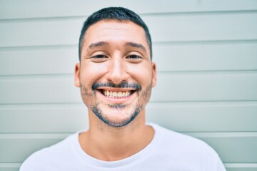 Sticker - Young hispanic man smiling happy walking at street of city.