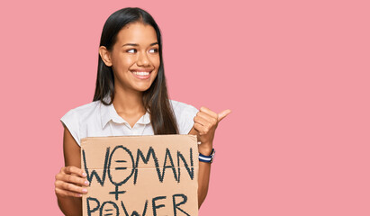 Sticker - Beautiful hispanic woman holding woman power banner pointing thumb up to the side smiling happy with open mouth