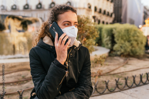 New normal. Teenager talking on the phone with a coronavirus mask. Young girl talking on the phone. Mask against covid. Teenager with face mask. Pandemic. Teenager talking.