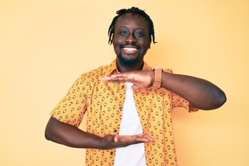 Sticker - Young african american man with braids wearing casual clothes gesturing with hands showing big and large size sign, measure symbol. smiling looking at the camera. measuring concept.