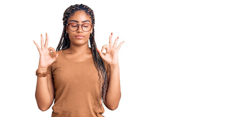 Wall Mural - Young african american woman with braids wearing casual clothes and glasses relax and smiling with eyes closed doing meditation gesture with fingers. yoga concept.