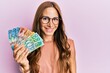 © Krakenimages.com - Young brunette woman holding australian dollars looking positive and happy standing and smiling with a confident smile showing teeth