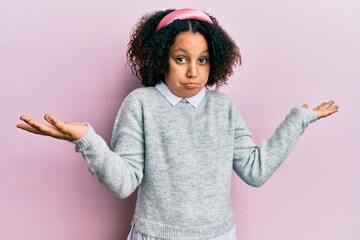 Poster - Hispanic little girl wearing casual clothes amazed and surprised looking up and pointing with fingers and raised arms.