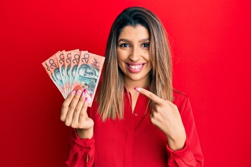 Poster - Beautiful brunette woman holding australian 20 dollars smiling happy pointing with hand and finger