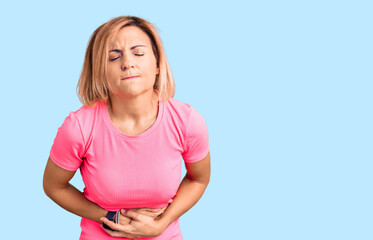 Wall Mural - Young blonde woman wearing sportswear with hand on stomach because indigestion, painful illness feeling unwell. ache concept.