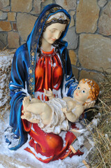   Nativity scene birth Jesus. Statuette of Maria with newborn Jesus on the hay covered with snow.