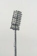 Stadium floodlight with metal pole, lighting mast, tower with floodlights in the sports stadium against the white sky.
