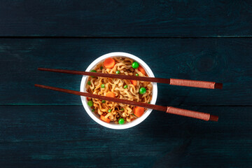 Wall Mural - Ramen cup. Instant noodles with chopsticks, shot from the top on a dark background