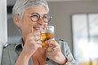 © goodluz - Cheerful 50-year woman drinking hot tea at home