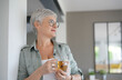 © goodluz - Cheerful 50-year woman drinking hot tea at home