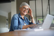 © goodluz - Portrait of a beautiful mature 50-year-old woman with white hair working from home