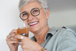 © goodluz - Cheerful 50-year woman drinking hot tea at home
