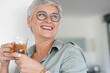 © goodluz - Cheerful 50-year woman drinking hot tea at home