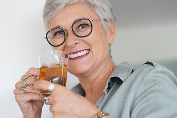 Wall Mural - Cheerful 50-year woman drinking hot tea at home