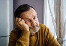Portrait Of Senior Man Wearing Sweater While Sitting At Home