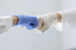 Doctors in rubber gloves touching their fists in clinic close-up. Health care workers cooperation concept