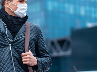 Wall Mural - close up. a serious man in a protective mask looks at the street of the city.