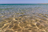 Fototapeta Morze - crystal clear sea water in shallow water with sun glare abstract background blur in motion