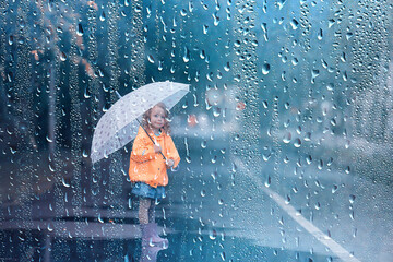 Wall Mural - little girl with an umbrella / small child, rainy autumn walk, wet weather child with an umbrella