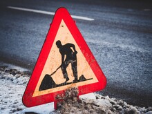 Close-up Of Men At Work Sign On Road