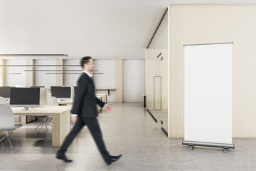 Poster - Businessman walking in loft coworking office with blank poster on wall.
