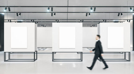 Aufkleber - Businessman walking in exhibition room with three blank banners on gray wall.