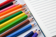 Close-up Of Colored Pencils With Blank Note Pad On Table