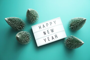 Wall Mural - Happy New Year word in light box with Christmas tree top view on blue background