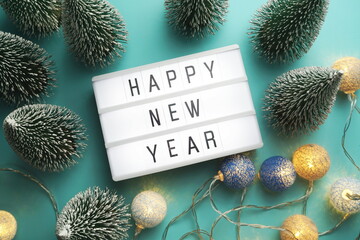 Wall Mural - Happy New Year word in light box with Christmas tree and LED cotton ball decorative top view on blue background