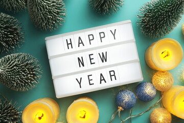 Wall Mural - Happy New Year word in light box with Christmas tree and LED cotton ball decorative top view on blue background