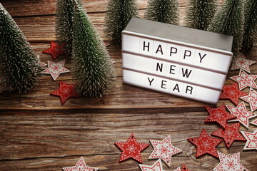 Wall Mural - Happy New Year word in light box with Christmas tree decoration on wooden background