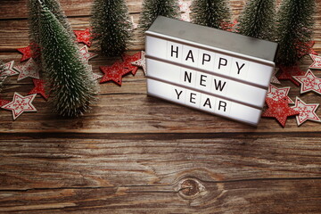 Wall Mural - Happy New Year word in light box with Christmas tree decoration on wooden background