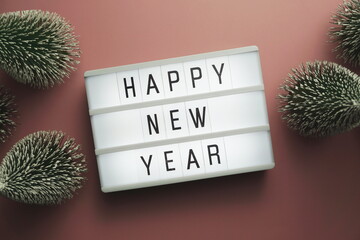 Wall Mural - Happy New Year word in light box with Christmas tree top view on pink background
