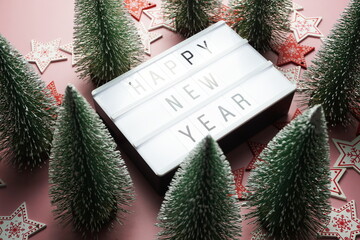 Wall Mural - Happy New Year word in light box with Christmas tree top view on pink background