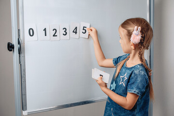 Portrait of sharming pretty beautiful kid arranging numbers in the correct order. Adorable child holding a card with number 5. Concept of mathematics. photo with noise