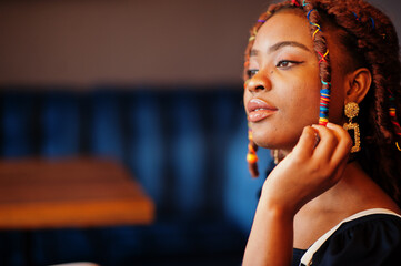 Wall Mural - Face portrait of lovely african american woman with dreadlocks at cafe. Beautiful cool fashionable black young girl indoor.