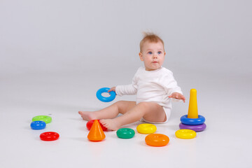 baby girl playing with colorful rainbow toy pyramid sitting on floor