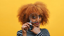 Funny Young African American Black Woman With Magnifier In Hand Shows Eye Through Magnifying Glass. High Quality Photo