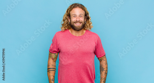 Fotomural blonde man looking happy and goofy with a broad, fun, loony smile and eyes wide
