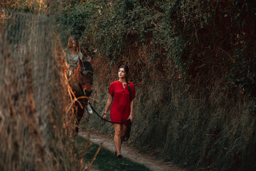 Wall Mural - Two women friends chatting and taking a ride with their horse through the countryside