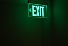 Close-up Of Illuminated Exit Sign Against Wall